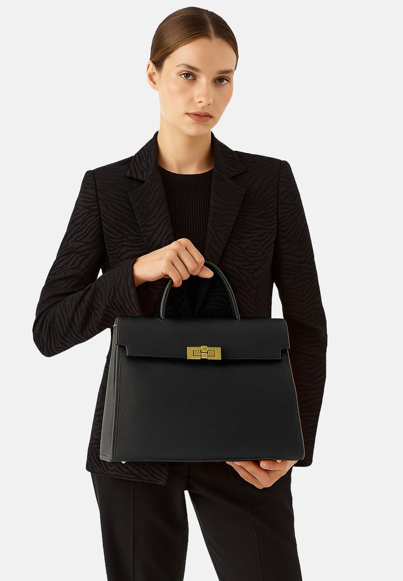 Borsa a mano in pelle nera con forma strutturata, manico superiore e dettagli metallici dorati. L'esterno presenta una superficie testurizzata e una chiusura a pattina.