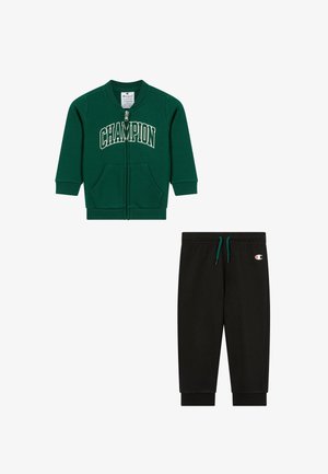 Giacca verde con cerniera e scritta "CHAMPION" e due tasche; pantaloni della tuta neri con coulisse turchese e logo Champion sull'anca.