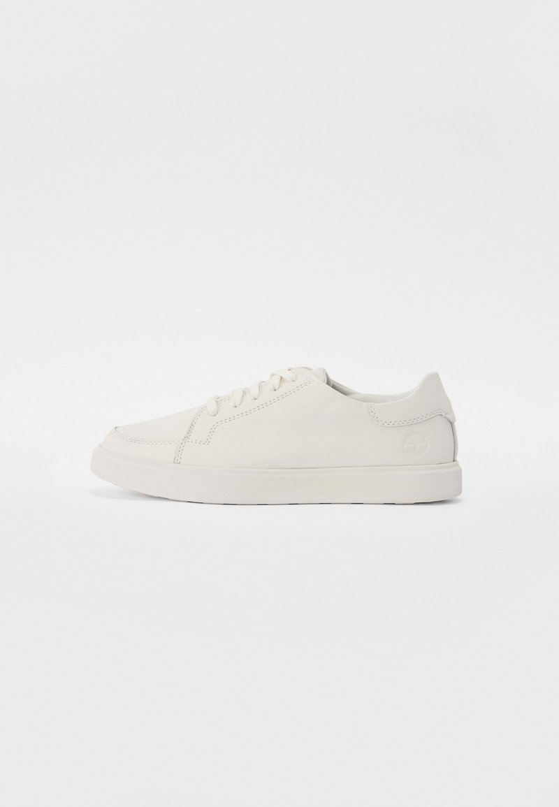 White sneakers made of smooth leather with a rounded toe and flat rubber sole. Features minimal stitching and a subtle logo on the side.