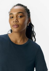 Navy blue, short-sleeve t-shirt made from a smooth fabric; features a crew neckline and minimalistic design, no patterns or accents visible.