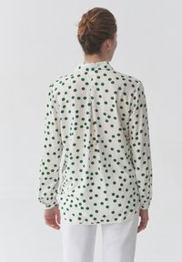 Camicia a maniche lunghe in tessuto bianco con pois verdi, dotata di colletto e polsini, texture liscia e taglio dritto.