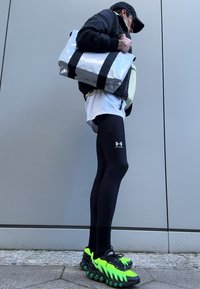 Svarte leggings, overdimensjonert hvit t-skjorte, svart bomberjakke og en sølvveske med svarte striper. Iøynefallende grønne og svarte joggesko.