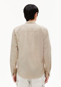 Beige und hellbraun gestreifte Langarmbluse mit Button-Down-Kragen, abgerundetem Saum und Ein-Knopf-Manschetten. Glatte Stoffoberfläche.