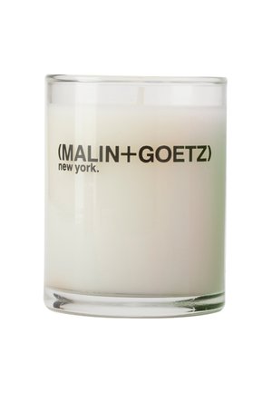 Weiße Kerze in einem klaren Glasbehälter mit der Aufschrift "MALIN+GOETZ new york" auf weißem Hintergrund, Docht sichtbar, aber unbeleuchtet.