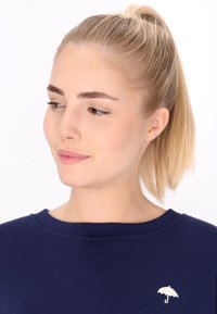 Mörkblå sweatshirt med rund halsringning, prydd med en liten vit paraplylogotyp på bröstet och en slät textur.