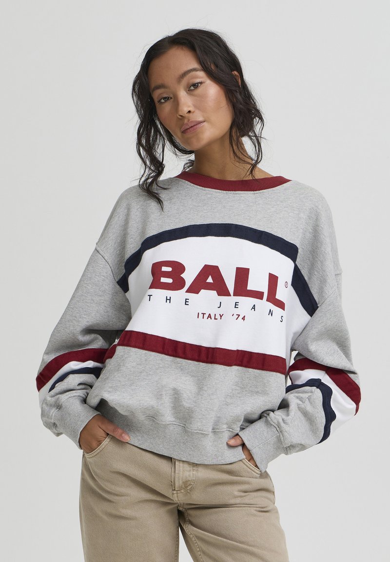 Sweat-shirt gris avec un col ras du cou côtelé, présentant de larges rayures rouges et bleu marine, et une impression graphique "BALL THE JEANS" et "ITALY '74".