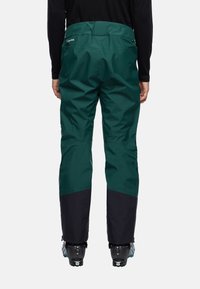 Groene skibroek met een zwart ondergedeelte, gemaakt van duurzame stof, met een taps toelopende snit en versterkte randen voor extra bescherming.