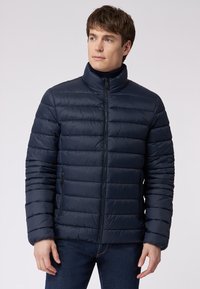 Dunkelblauer, wattierter Mantel mit horizontalem Steppmuster, hohem Kragen und Reißverschluss. Verfügt über Seitentaschen und eine elegante, glatte Textur.