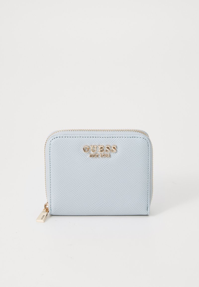 Portefeuille texturé bleu clair avec un logo en métal doré et une fermeture à glissière, de forme carrée et présentant des détails de couture visibles.