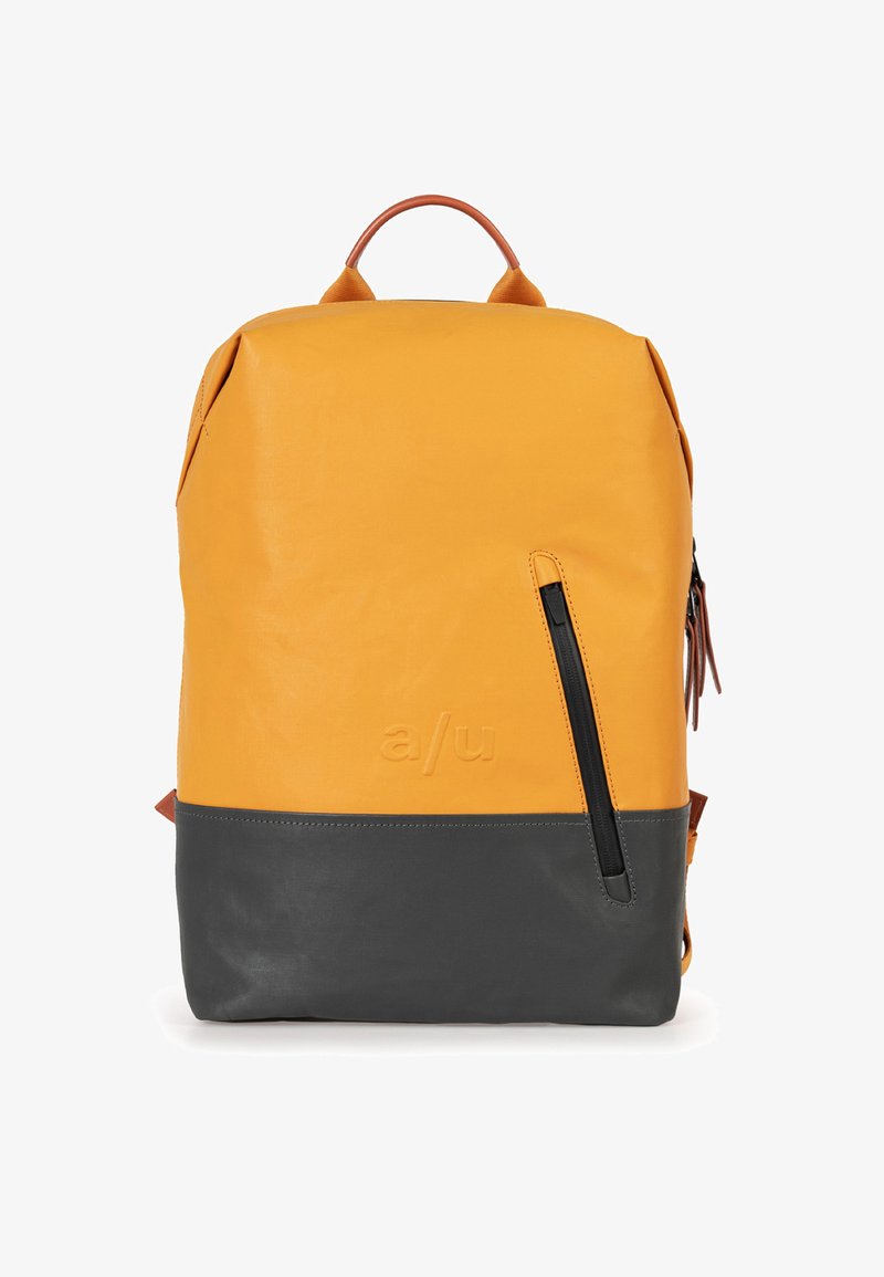 Geel leren rugzak met een donkergrijze onderkant, voorzien van een zijrits zak en een leren handvat aan de bovenkant. Minimalistisch ontwerp met het merklogo.