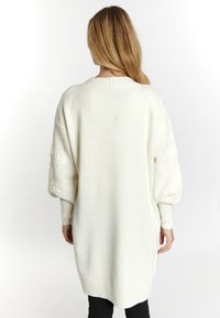 Fehér, oversized pulóver texturált, puffos ujjakkal. Ribbed mandzsettákkal és hem, puha kötött anyaggal és kerek nyakkivágással rendelkezik.