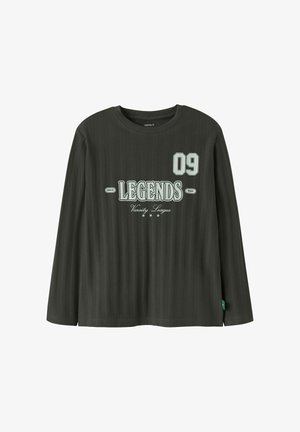 Chemise côtelée à manches longues vert foncé avec texte sur la poitrine "09 LEGENDS Since 1986 Varsity League" et trois petites icônes d'étoiles sous le texte.