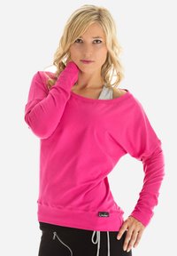 Roze sweatshirt met lange mouwen, wijde hals en een relaxte pasvorm. Zachte textuur en aansluitende manchetten, met een klein merklabel aan de zoom.