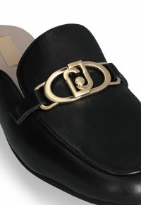 Chaussure noire en cuir à enfiler avec un bout arrondi, présentant un détail de boucle dorée proéminent à l'avant et une surface lisse.