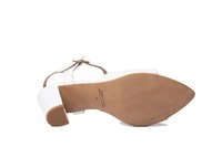 Sandalia de tacón blanca con un acabado suave, punta abierta y correa ajustable en el tobillo. Suela plana marrón con textura acanalada y detalles en relieve.