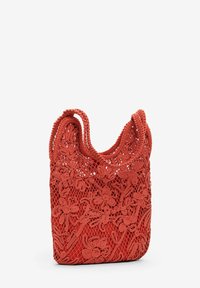 Rød hæklede taske med blomsterprint og et netmønster, med to håndtag og en blød, fleksibel struktur.