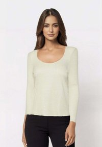 Maglia a maniche lunghe con scollo a barca in tessuto testurizzato color crema chiaro, abbinata a pantaloni neri, caratterizzati da una vestibilità comoda e un design semplice.