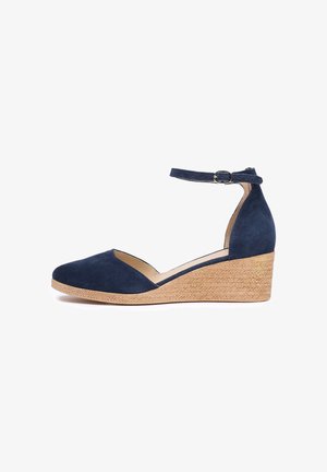Navy blue suede wedge shoe with adjustable ankle strap, jute-wrapped heel, and closed toe design. Smooth texture and simple shape.