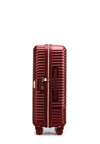 Valise rigide rouge métallique avec des ridges verticales, une serrure à combinaison et deux roues robustes. Dispose d'une fermeture éclair lisse.