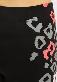 Sorte leggings med et grått og rosa leopardmønster. Myk, elastisk stoff med en glatt tekstur og en elastisk livlinje.
