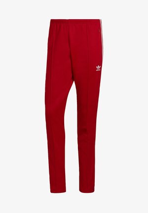 Red athletic pants with an elastic waistband, side zip pockets, and three white stripes down the sides. Features a small logo on the thigh.