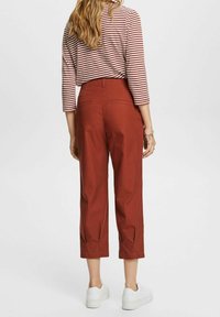 Rode cropped broek van katoen, met zijzakken en een hoge taille. Gecombineerd met een gestreepte lange mouwen top en witte sneakers.