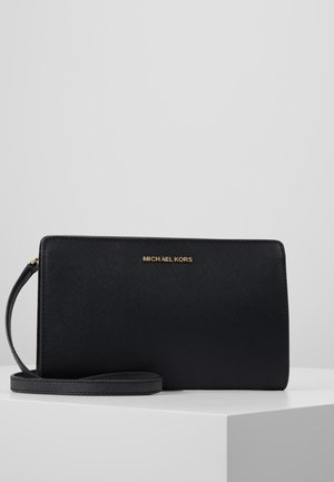 Black Michael Kors wallet with a textured exterior, gold logo, zip closure, and detachable strap, rectangular shape and smooth edges.