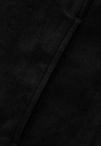 Texture di tessuto scamosciato nero con una superficie liscia e leggere variazioni. Presenta cuciture per dettagli strutturali.