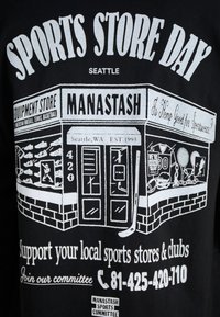 Black t-shirt featuring white graphic of a sports store with text, sports equipment, and details about the store location and events.