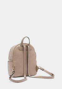 Zaino in pelle beige con motivo trapuntato, forma arrotondata, spallacci regolabili e dettagli in tonalità oro. Include una tasca laterale.