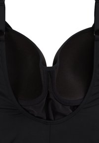 Juodas paminkštintas liemenėlės su reguliuojamais petnešėliais, lygiu audiniu ir formuotomis kaušelėmis, skirtomis palaikymui ir formavimui.