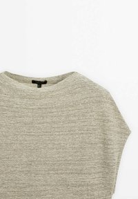 Pull en tricot gris clair à col rond, étalé à plat sur un fond blanc, montrant la texture et les détails du tissu.