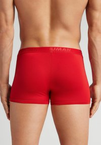 Boxer ajustados rojos hechos de una tela suave, con una amplia cinturilla elástica con una marca en relieve. El diseño ceñido resalta la forma.
