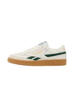 Zapatilla Reebok blanca de perfil bajo con rayas verdes en el lateral y suela de goma color caramelo, vista desde el lado exterior.