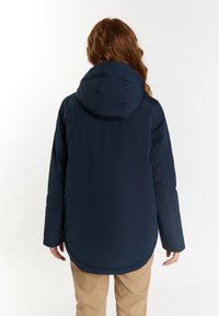 Giacca imbottita blu navy con cappuccio, caratterizzata da un orlo curvo e una vestibilità rilassata. Tessuto liscio e dettagli di cucitura minimi sul retro.