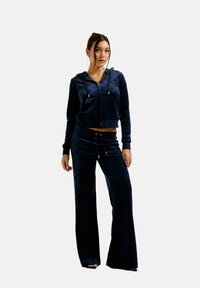 Navy blue velour tracksuit featuring a cropped zip-up hoodie with a hood and wide-leg pants, both with a subtle pattern and drawstring accents.
