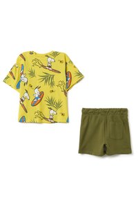 Camicetta gialla a maniche corte con stampa di Snoopy che fa surf, abbinata a pantaloni corti con cintura elastica verde e tasca sul retro.