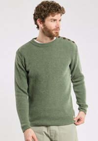 Zielony sweter w prążki z okrągłym dekoltem, długimi rękawami i brązowymi guzikami na ramionach. Wykonany z materiału o teksturowanym splocie.