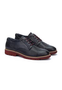 Chaussures en cuir noir avec un design perforé, lacets rouges, semelle en caoutchouc et surpiqûres contrastantes en tan. Bout arrondi et silhouette classique.