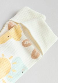 Bomullstrumpor med en ljusgul ribbad textur, med ett mönster av sol och björn i pastellfärger, med rundade muddar upptill.