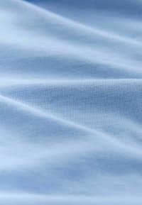 Țesătură albastru deschis cu o textură fină și un model discret în dungi, prezentând pliuri moi și un aspect uniform pe toată suprafața.