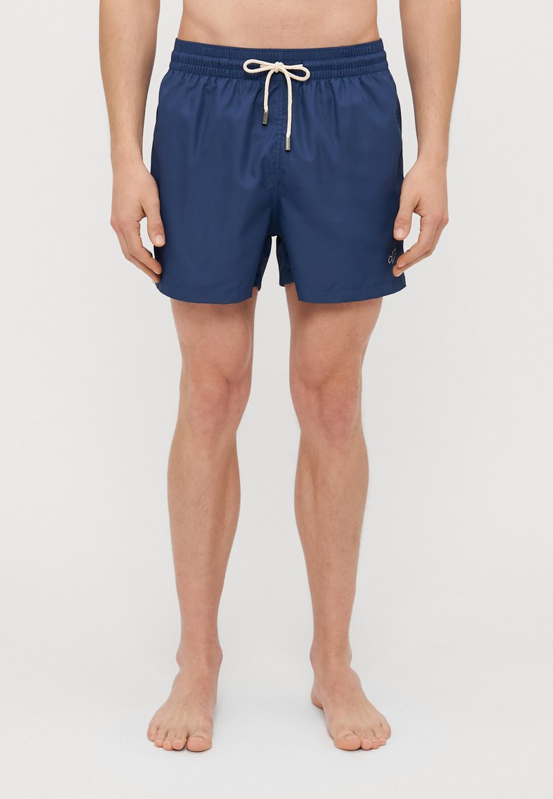 Marineblaue Badehose mit elastischem Bund, verstellbarem Kordelzug und seitlichen Taschen. Glatte Textur, mittellange Beinlänge, einfaches Logodesign.