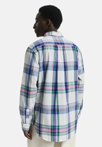 Camisa de cuadros blanca con patrones de cuadros en azul, verde y rosa. Cuenta con un cuello tipo button-down y una tela texturizada. Mangas largas con puños.