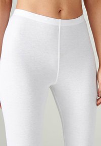 Leggings de algodón blancos con textura acanalada, que cuentan con una cinturilla elástica y un diseño ajustado, destacando un aspecto suave y minimalista.