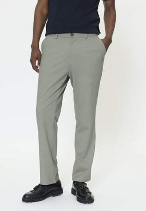 Világosszürke, texturált felületű, szabott nadrág, gombos záródással és oldalzsebekkel, fekete elegáns cipőkkel párosítva.