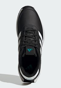 Svart idrettssko med en teksturert skinnoverdel, hvite striper, svarte snørebånd og en grønn detalj på tungen. Rund tådesign.