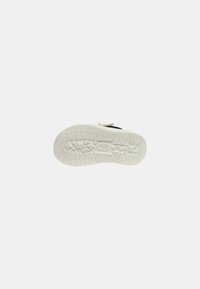 Suola di sneaker bianca in gomma con un motivo testurizzato per la presa, caratterizzata da scanalature per la trazione e una forma arrotondata. Rivestita con una finitura liscia.