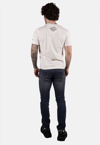 T-shirt da uomo in cotone bianco con scollatura rotonda, maniche corte e un piccolo logo stampato sulla parte superiore della schiena; abbinato a jeans blu slim-fit.