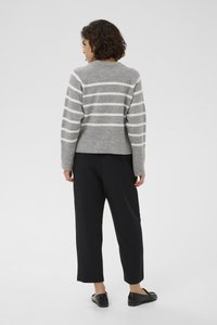 Pull en maille rayé gris avec des lignes blanches horizontales, ourlet et poignets côtelés. Associé à un pantalon large noir et des chaussures noires.
