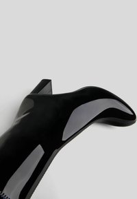 Czarne lakierowane botki za kostkę z szpiczastym noskiem i wąską szpilką. Gładkie, błyszczące wykończenie z kontrastującym przeszyciem wzdłuż krawędzi.